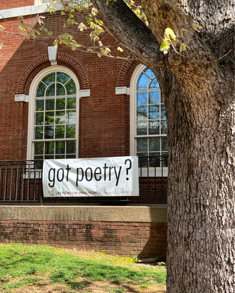 A white banner with black lettering saying “Got Poetry?” is displayed on the porch of JMRL’s Central Library in downtown Charlottesville to celebrate National Poetry Month.